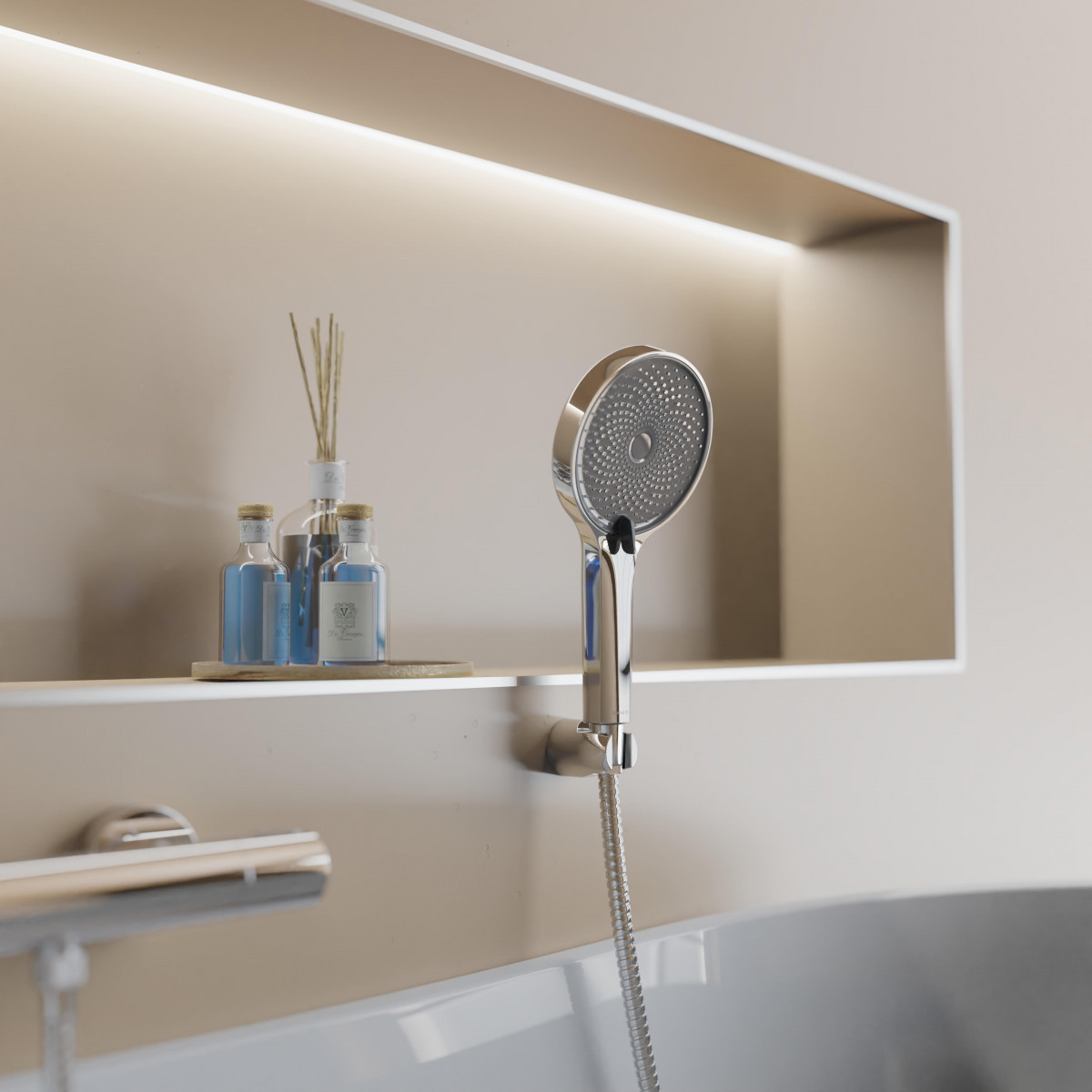 Chromfarbene Handbrause mit flexiblem Schlauch an Wandhalterung über Badewanne.