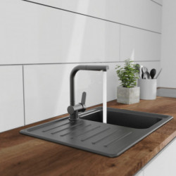 Schwarze Küchenarmatur mit Hebel über Edelstahlspüle mit Abtropffläche und laufendem Wasser