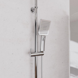 Handbrause mit eckigem Duschkopf an verchromter Duschstange an Wand montiert.