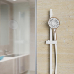 Handbrause mit verstellbarer Wandhalterung und flexiblem Schlauch an beiger Fliesenwand