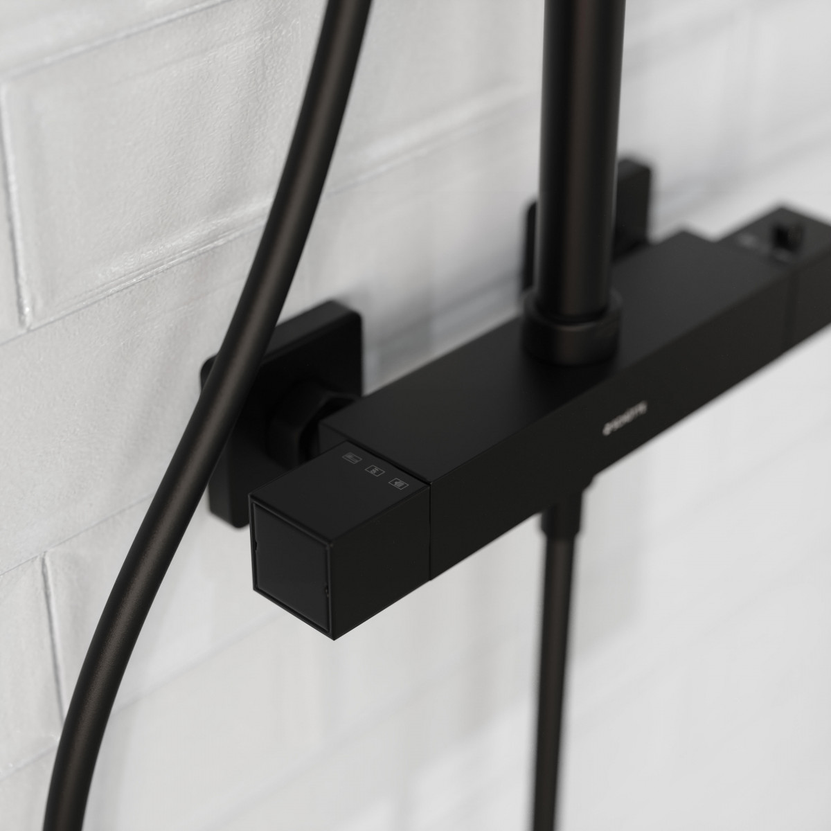 Detailansicht einer schwarzen Wandarmatur mit eckigem Regler und Rohranschluss