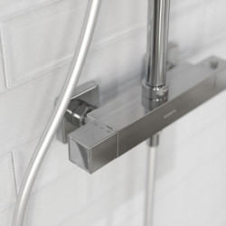 Detail einer verchromten Duscharmatur mit eckigem Thermostat an Fliesenwand