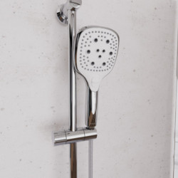 Chromfarbene Handbrause mit Brauseschlauch und Wandhalterung an Duschstange