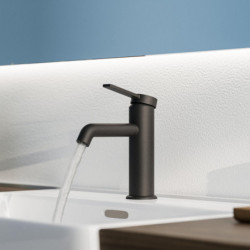 Schwarze Waschtischarmatur mit Hebelgriff, Wasser läuft in weißes Waschbecken.