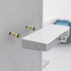 Zwei Messing-Gewindeanschlüsse an der Wand unter einem Heizkörper.