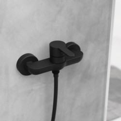 Schwarze Duscharmatur mit Einhebelmischer und angeschlossenem Duschschlauch an grauer Wand.